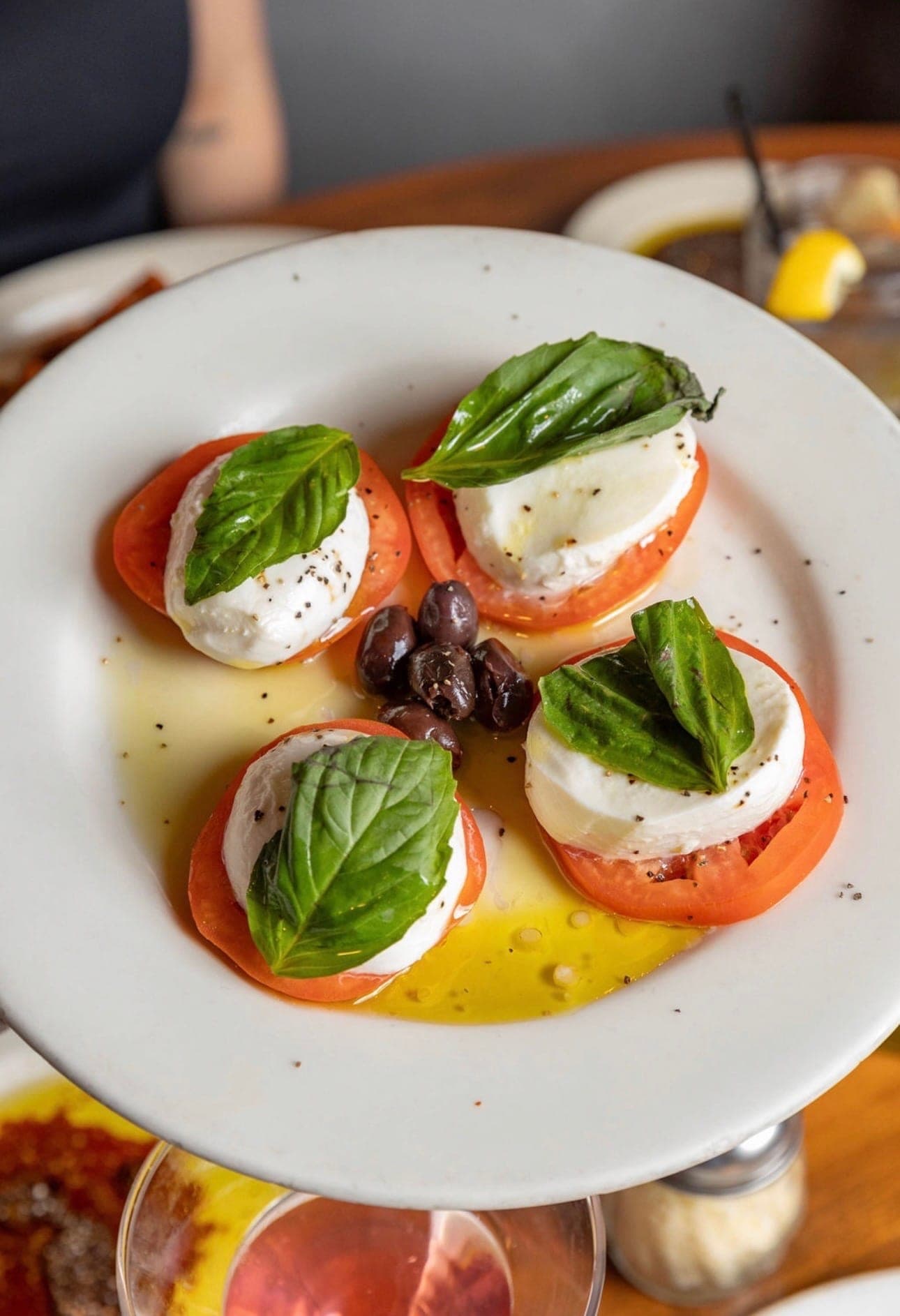 Buffalo mozzarella caprese with basil, tomato, and olives.