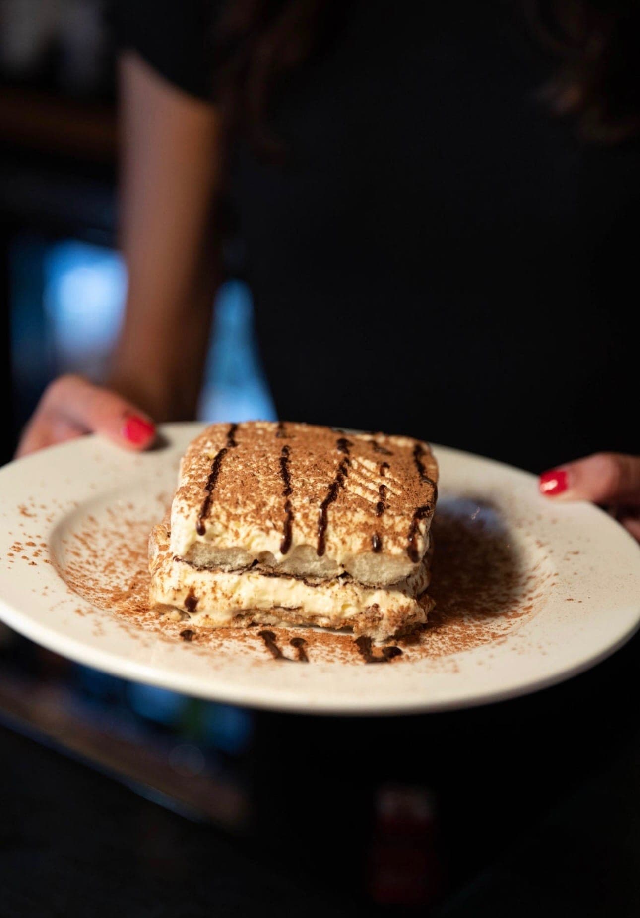House-made tiramisu dusted with cocoa, served by a Nick's host.